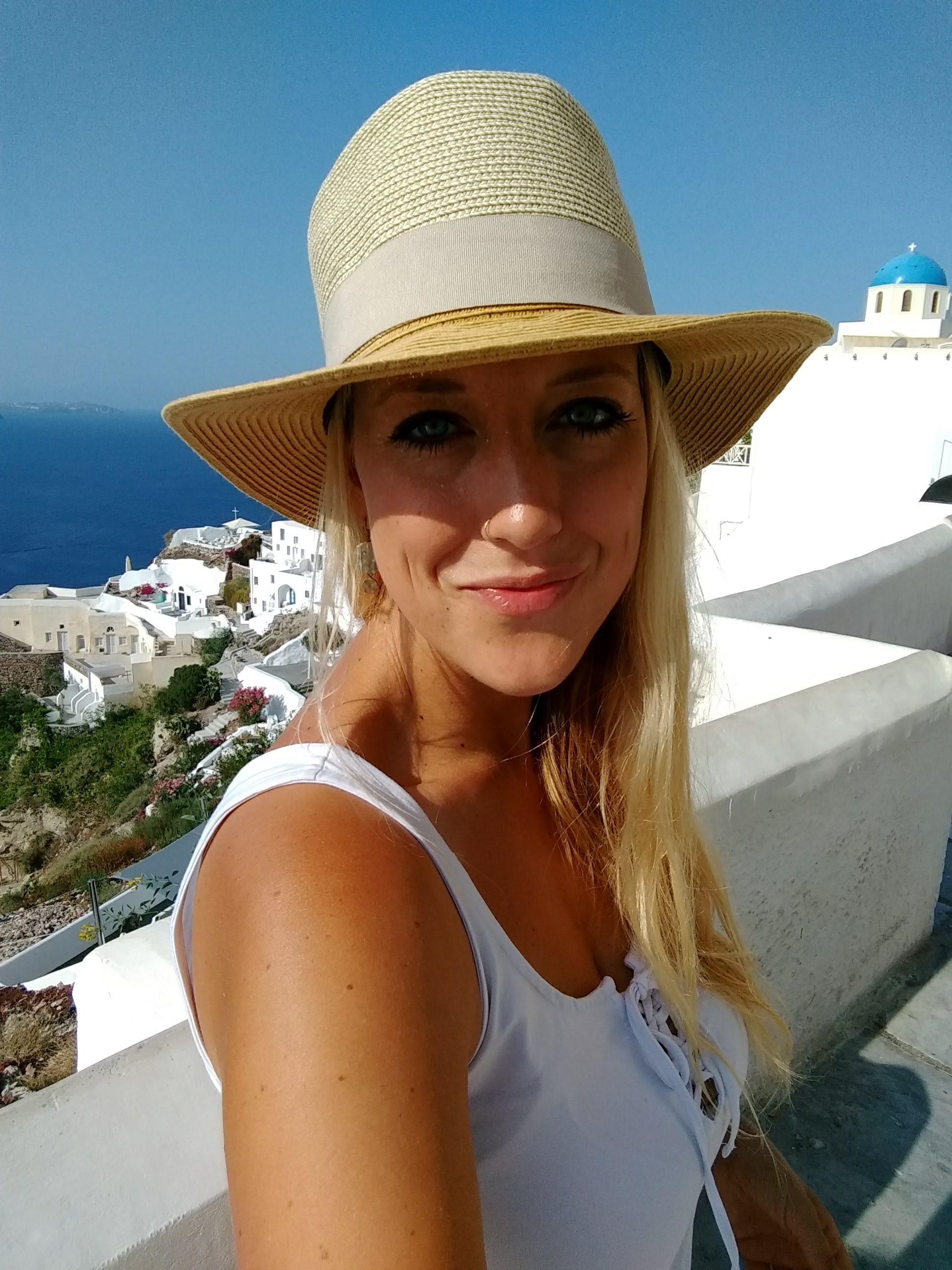 Picture of girl wearing a hat with Santorini, Greece in the background 